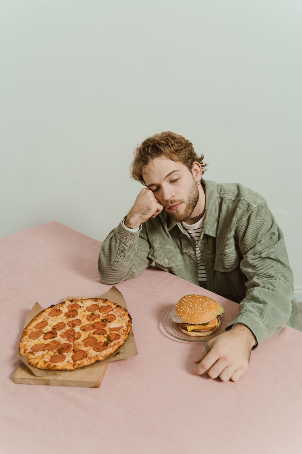 A person sitting at a table looking wearily at fast food