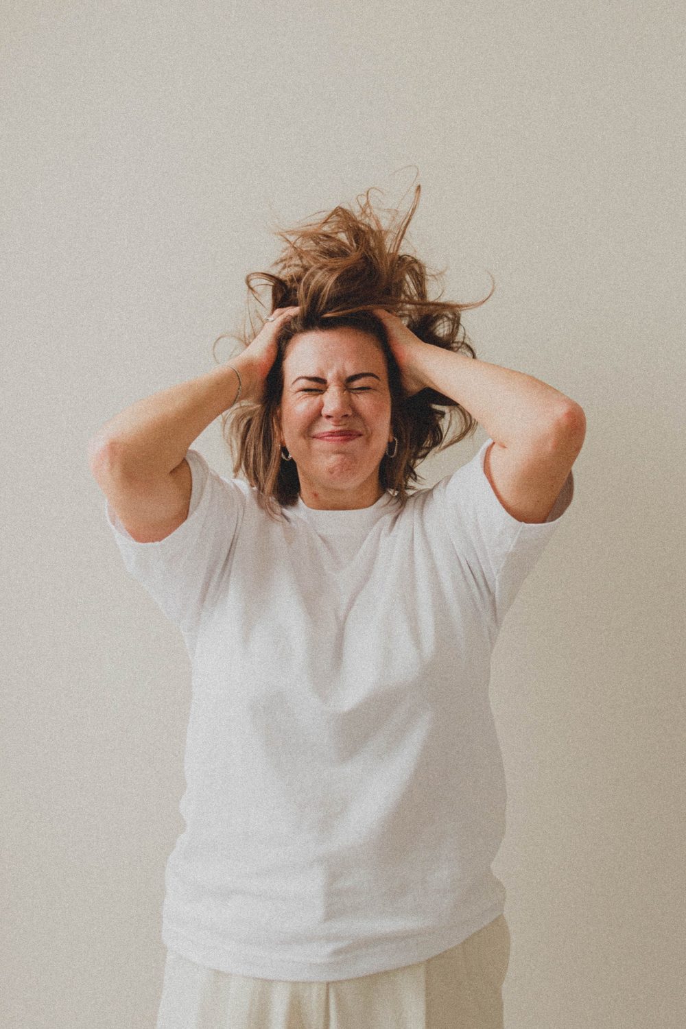 A person running her hands through her hair in frustration
